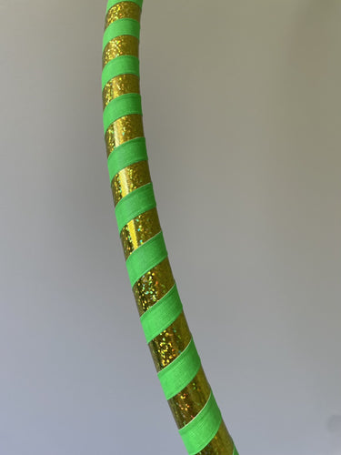 Hula hoop for beginners with gold and green striped pattern on a plain background
